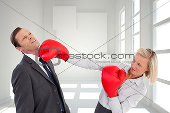 Composite image of businesswoman hitting colleague with her boxing gloves