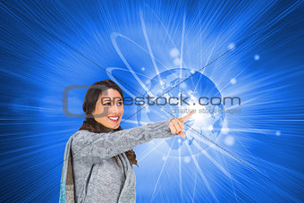 Composite image of smiling brunette wearing winter clothes pointing out