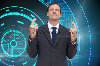 Composite image of serious businessman with fingers crossed is looking up