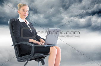 Composite image of businesswoman sitting in swivel chair with laptop