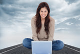 Composite image of woman sitting on the bed with the laptop in front of her and smiling