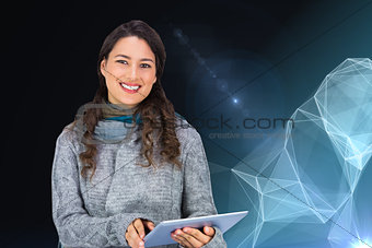 Composite image of smiling model wearing winter clothes holding her tablet