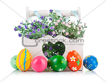 easter eggs in wooden basket with spring flowers