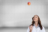 Composite image of happy doctor throwing apple