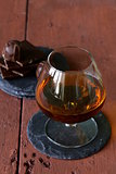 glass of brandy with chocolate on wooden table