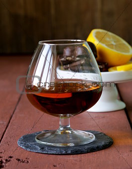 glass of brandy with chocolate on wooden table