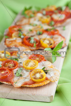 Mini pizzas with mozzarella, cherry tomatoes and basil