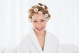 Beautiful woman in bathrobe and hair curlers at home