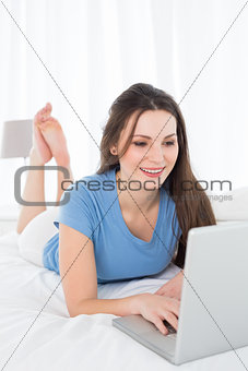 Beautiful smiling woman using laptop in bed
