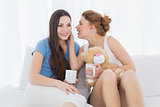 Female friends with coffee cups gossiping in bed