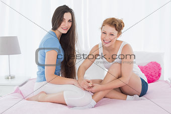 Cheerful woman painting friends nails on bed