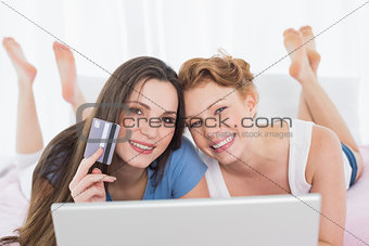 Relaxed female friends  doing online shopping in bed