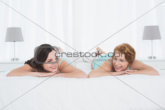 Two smiling female friends in lying in bed