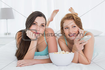 Friends with remote control and popcorn in bed