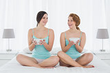 Female friends with salad bowls sitting on bed