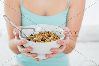 Mid section of a female with a bowl of cereal in bed