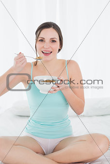 Female with a bowl of cereal sitting on bed