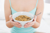 Mid section of a female with a bowl of cereal sitting on bed