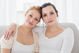 Smiling female friends with arm around in living room