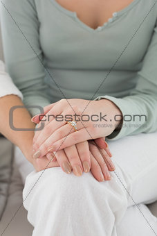 Close-up mid section of female friends touching hands