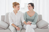 Woman consoling female friend while sitting on sofa
