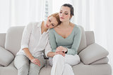 Young woman consoling female friend on sofa