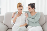 Young woman consoling female friend at home