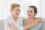Cheerful female friends embracing in living room