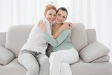 Cheerful young female friends embracing in living room