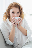 Thoughtful young woman drinking coffee at home
