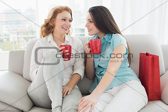 Female friends with coffee cups conversing at home
