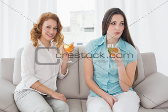 Female friends with wine glasses sitting on sofa