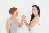 Portrait of two casual young female friends arm wrestling