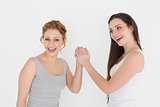 Portrait of two casual young female friends arm wrestling