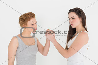 Two serious young female friends arm wrestling