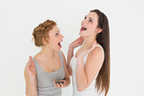 Shocked casual young female friends with mobile phone
