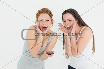 Shocked cheerful female friends with mobile phone