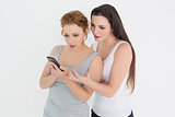 Two casual young female friends looking at mobile phone