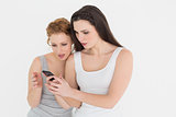 Two casual young female friends looking at mobile phone