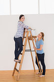 Female friends with a ladder in a new house