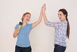 Two cheerful young female friends giving high five