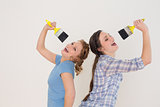 Cheerful female friends singing into paintbrushes