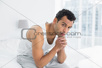 Portrait of a serious man sitting on bed