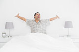 Cheerful man stretching his arms in bed