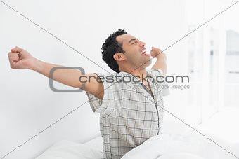 Young man stretching his arms in bed