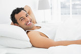 Cheerful young man resting in bed