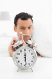 Blurred man in bed extending hand to alarm clock