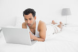 Casual man using laptop in bed