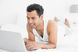 Casual man using laptop in bed