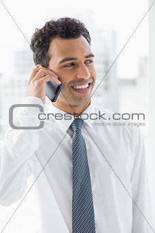 Smiling elegant young businessman using cellphone
